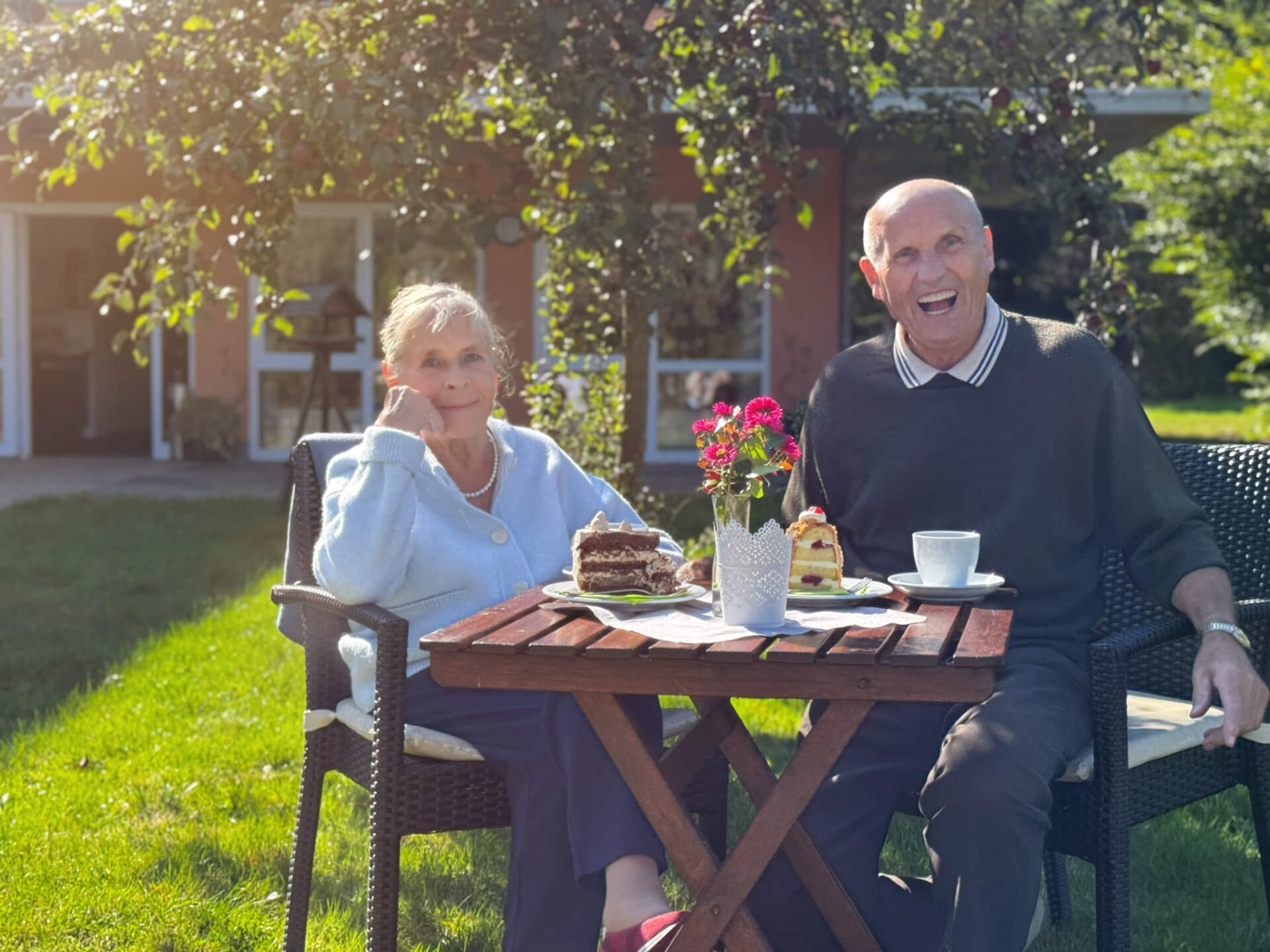 Bewohner sitzen im Garten mit einem Stück Kuchen und einer Tasse Kaffee