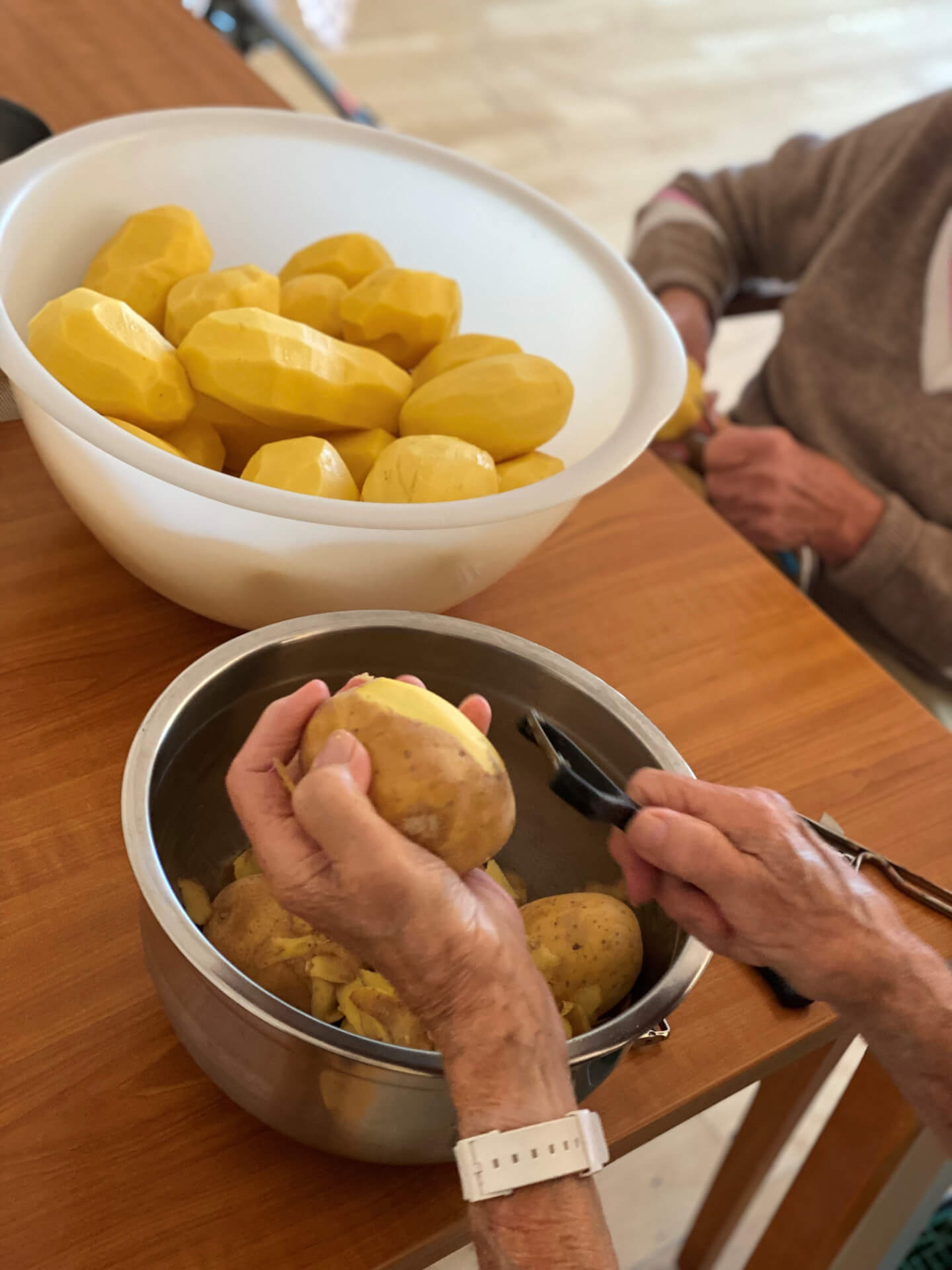 Bewohner an einem Tisch, die Kartoffeln schälen